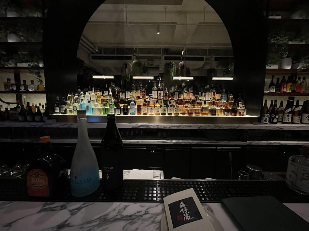 シェラトン鹿児島のバー VIVARIUM のカウンター越しに並ぶボトル群。焼酎やクラフトジンなどご当地のお酒も充実