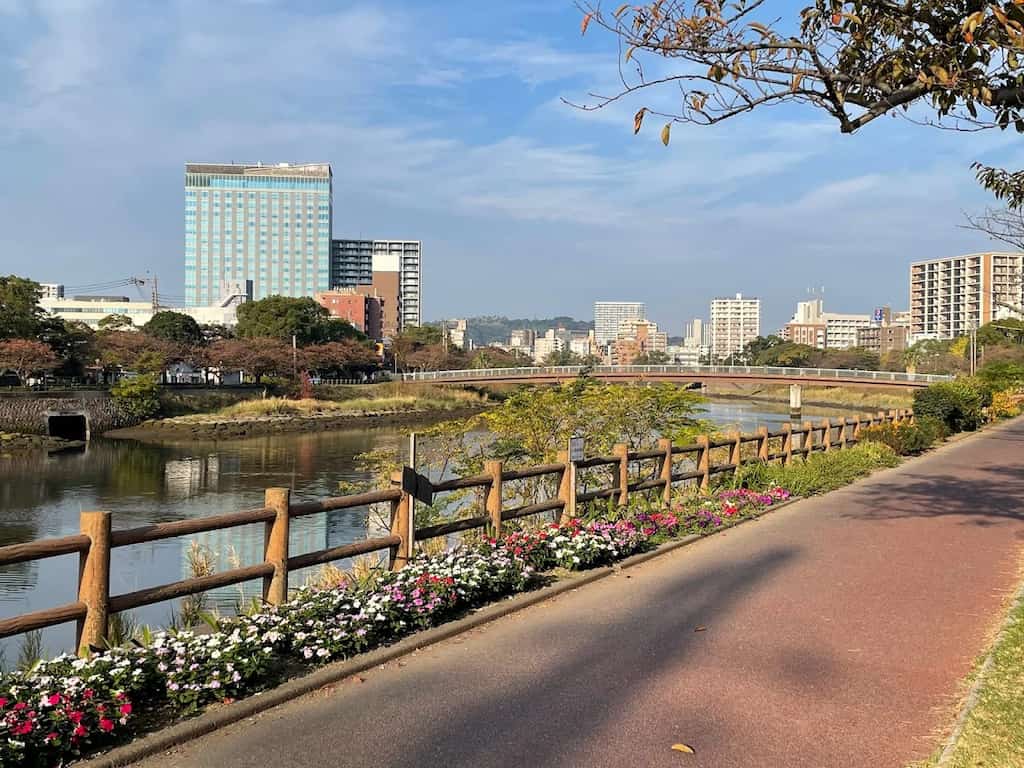 甲突川沿いの遊歩道から望むシェラトン鹿児島。花壇やベンチも整備され、散歩や気分転換に最適な周辺環境