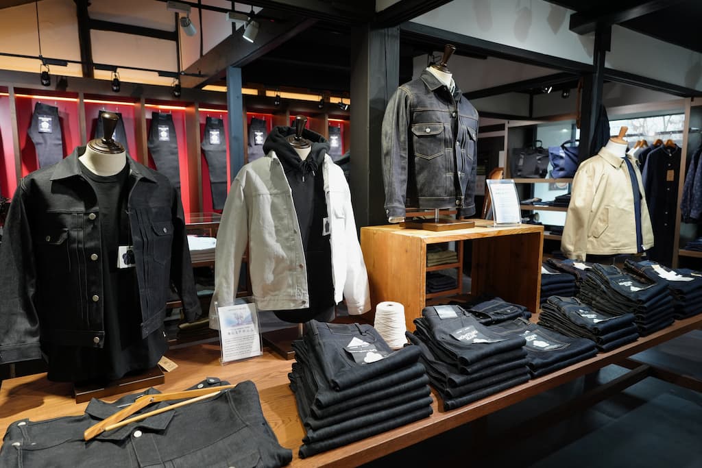 児島ジーンズストリートにある桃太郎ジーンズの店内。ジーンズやジージャンが並び、日本製デニムの品質と存在感を感じられる。